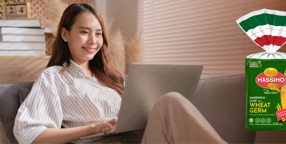 Woman working on a laptop with a sandwich